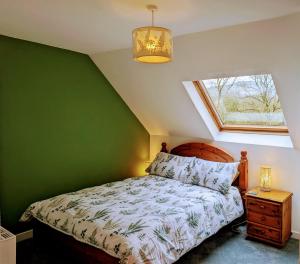 1 dormitorio con cama y pared verde en Ty Madog, en Cwm-y-glo