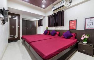 - une chambre avec un grand lit rouge et des oreillers violets dans l'établissement Hotel Niyati Guest House, à Vieux-Goa