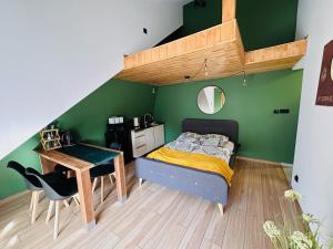 1 dormitorio con cama, escritorio, cama y pared verde en U Babci na strychu en Zakopane