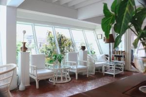 a room with white chairs and tables and windows at Vimala Suites in Bangkok