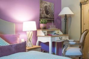 バート・アウスゼーにあるWaldruhe - Bett, Frühstück & ein Lächelnの紫の壁のベッドルーム(ランプ付きテーブル付)