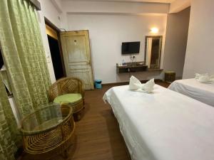 una camera d'albergo con due letti e un tavolo con sedie di Lamahatta Residency a Darjeeling