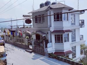una grande casa bianca con una strada di Lamahatta Residency a Darjeeling