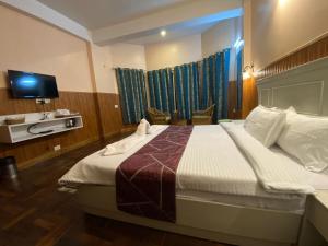 a bedroom with a large bed with a tv on the wall at Lamahatta Residency in Darjeeling