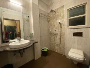a bathroom with a sink and a shower and a toilet at Lamahatta Residency in Darjeeling