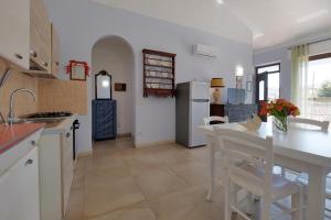 una cucina con tavolo e sedie in una stanza di CASA AZZURRA - BLUE HOUSE a Teulada
