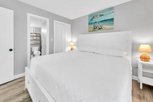 a white bedroom with a white bed and a bathroom at Edgewater Tower 2-108-Gunners Paradise in Panama City Beach