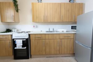 una cucina con armadi in legno e frigorifero bianco di Centrally Located 1Bed Apt in Stretford a Manchester