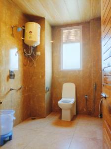 a bathroom with a toilet and a window at sky hill house in Manāli