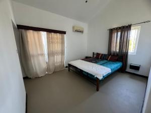 a small bedroom with a bed and two windows at Villa Piefraper in Grand Gaube