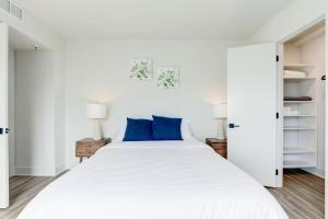 a white bedroom with a large bed with blue pillows at 2BR Comfort Apartment in Prime Location in Arlington