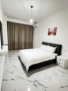 een slaapkamer met een groot wit bed en marmeren vloeren bij Prime Luxury Apartments in Lushnjë