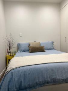 ein großes Bett mit blauen Kissen im Schlafzimmer in der Unterkunft Exquisite Inner City Modern 1 Bedroom Apt in Sydney