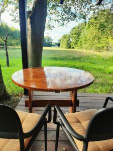 a wooden table and chairs on a porch with a tree at Domek na odludziu in Sarnaki