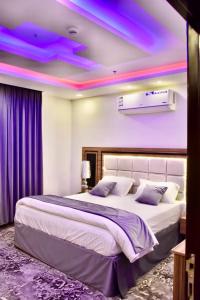 1 dormitorio con 1 cama grande con luces moradas en el techo en رست بست للشقق المخدومة, en Al Mikhlaf