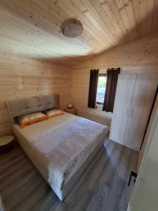 een slaapkamer met een bed in een houten hut bij Kucica Una in Ulcinj