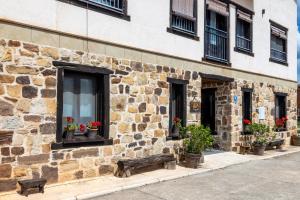 a stone building with flowers in windows and a bench at Hotel Valdelinares (Soria) in Valdelinares