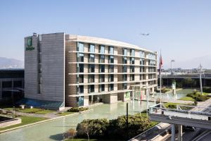 un edificio con un río delante de él en Holiday Inn Santiago - Airport Terminal by IHG, en Santiago