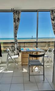 einen Tisch und Stühle auf einem Balkon mit Blick auf den Strand in der Unterkunft STUDIO BELLE PLAGE in Leucate