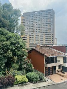 a tall building in front of a building with a house at Casa Céntrica a 5 min Metro y Mayorca in Envigado