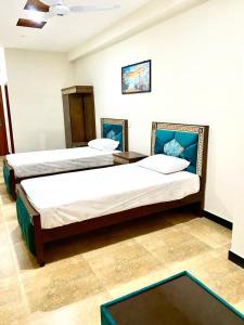 um quarto de hotel com duas camas e uma mesa em Faisal Lodges em Islamabad