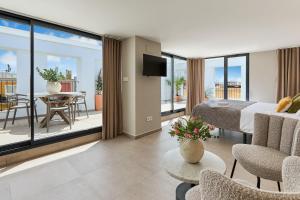 a bedroom with a bed and a balcony with a table at El Pont Alicante Apartments in Alicante