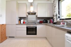 a white kitchen with white cabinets and a sink at Heronlea Cottage in Dunoon