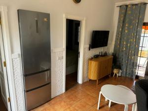 een keuken met een koelkast en een tafel en een televisie bij Bungalow near Yumbo in Playa del Inglés
