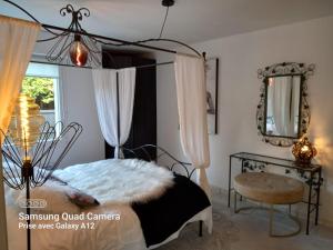 a bedroom with a canopy bed and a chair at Le Cocon du Verger in Baldersheim