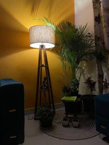 a lamp on a tripod in a room with plants at Your Own Sweet Nest in Gwalior with comfort in Gwalior
