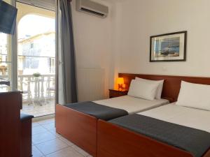 a hotel room with two beds and a balcony at Korali Hotel in Paralia Katerinis