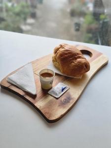 a wooden cutting board with a croissant and a cup of coffee at Star Hotel Astir in Tirana