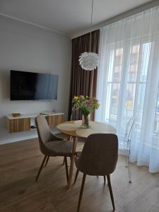 a living room with a table and chairs and a television at Apartamenty Piekarczyk - Elbląg in Elblag