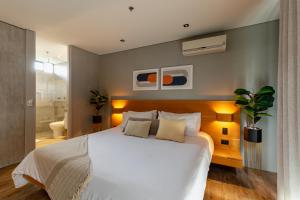 1 dormitorio con 1 cama blanca grande y baño en Loma Verde Aparthotel, en Medellín