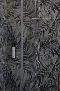 a shower in a bathroom with a leafy wall at JOHN'S ROOMS in Villa D'agri