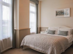 a bedroom with a large bed and windows at 4 The Salcombe in Salcombe
