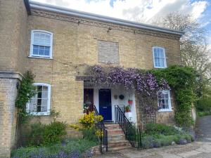 uma casa de tijolos com uma porta azul e flores em The Old Mill Cottage em Fakenham