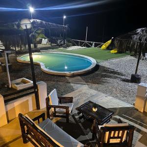 una piscina notturna con sedie e tavolo di puntacanoas bungalows a Canoas