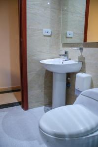 a bathroom with a white toilet and a sink at Hotel ByHours Las Américas in Bogotá