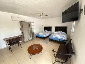 Habitación con 2 camas, mesa y TV. en Apartamentos Amplios Alfa # 238, en Monterrey