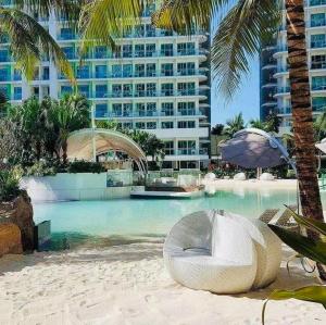 a swimming pool with a beach chair and a building at The Bahamas & Maldives Suites at Azure Residences near Manila Airport in Manila