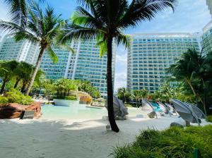 a resort with a beach with palm trees and a building at The Bahamas & Maldives Suites at Azure Residences near Manila Airport in Manila