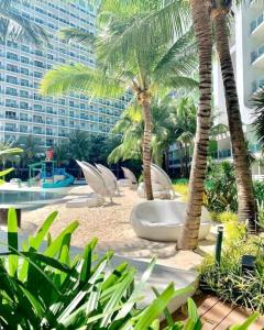 a resort with palm trees and chairs and a building at The Bahamas & Maldives Suites at Azure Residences near Manila Airport in Manila