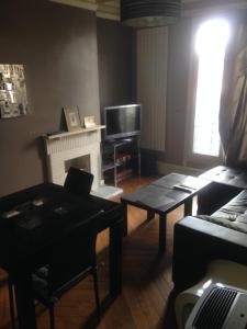 a living room with a couch and a table and a tv at Chambre privative dans appartement sur Paris in Paris
