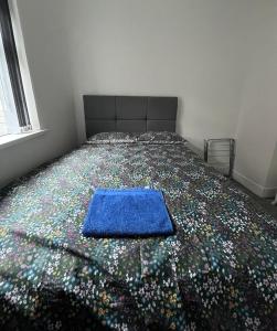 a bed with a blue blanket on top of it at Snugly Studio Flat near Talbot Pub in Birmingham