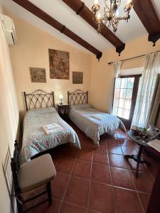 a bedroom with two beds and a table and window at Casa Rural Tita Sacramento in Hornachos