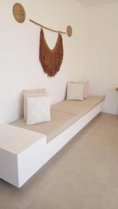 a white bed with pillows on a white wall at Conforto e Charme, Casa a 360m da Areia in Porto Seguro