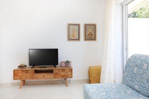 a living room with a tv on a wooden cabinet at Bohemian Dreamscape #PROPERTLY in Hanioti