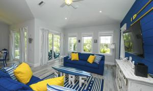 uma sala de estar com um sofá azul e almofadas amarelas em Anna Maria Beach House, 5 beds 6,5 baths, roof-top deck and pet-friendly! em Anna Maria