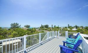 zwei blaue Stühle auf einer Terrasse mit Strand in der Unterkunft Anna Maria Beach House, 5 beds 6,5 baths, roof-top deck and pet-friendly! in Anna Maria